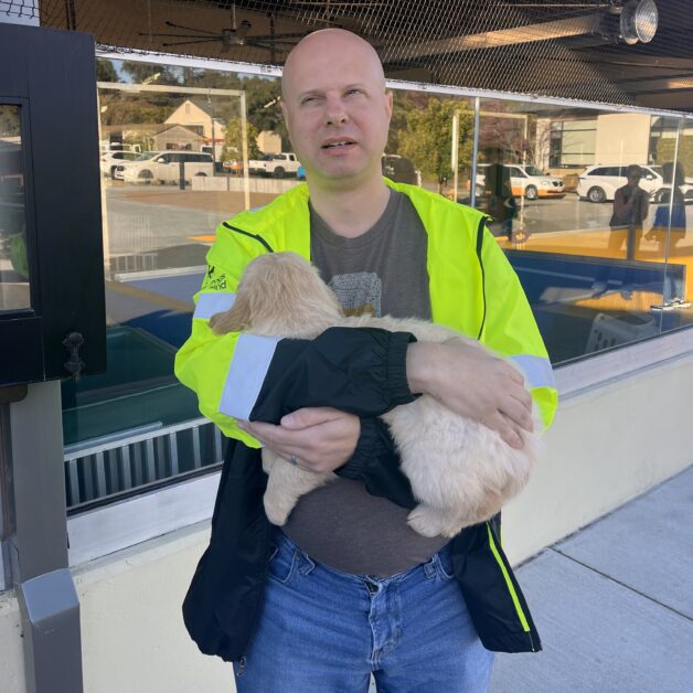 Chris Peterson holding a golden colored puppy