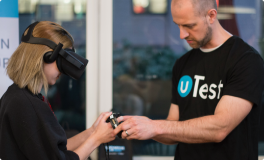 a uTest researcher placing a controller in the hands of a study participant who is wearing VR glasses.